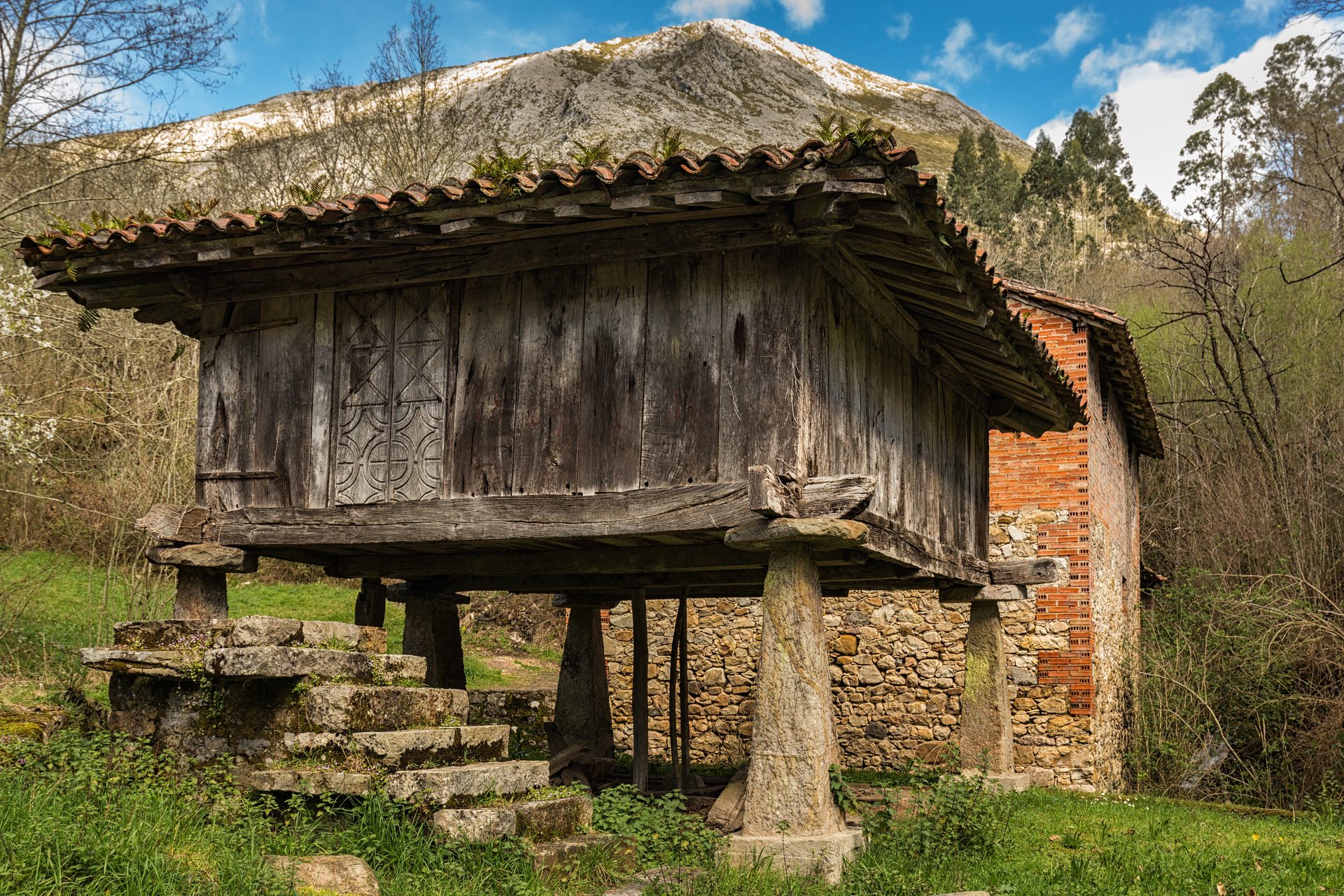 Hórreo asturiano tradicional con pegollos de madera y cubierta de teja árabe en Asturias